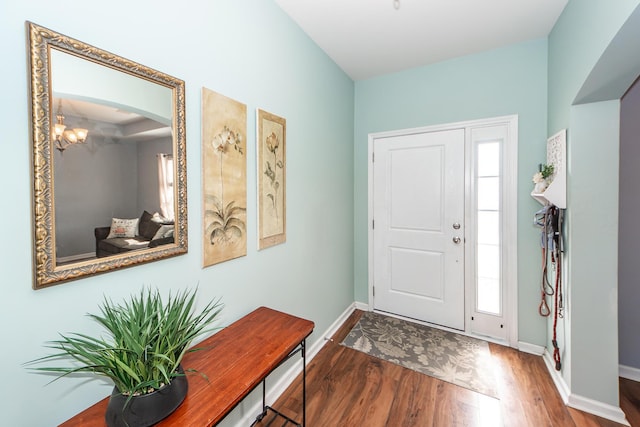 entrance foyer featuring baseboards, arched walkways, and wood finished floors