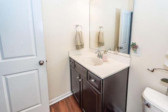 bathroom with baseboards, vanity, toilet, and wood finished floors