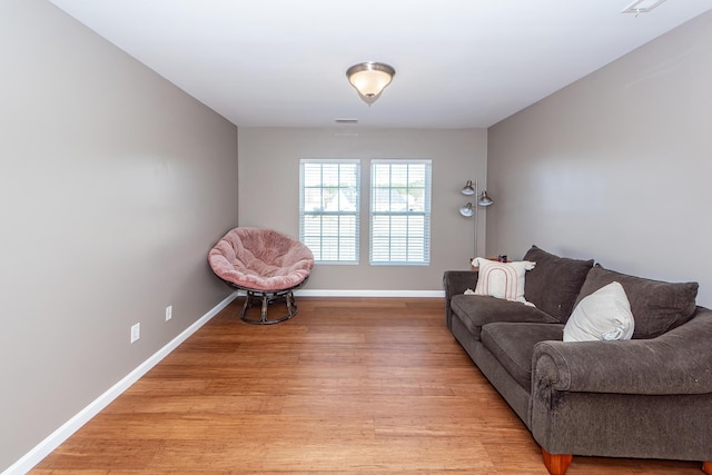 living area featuring light wood-style floors, visible vents, and baseboards