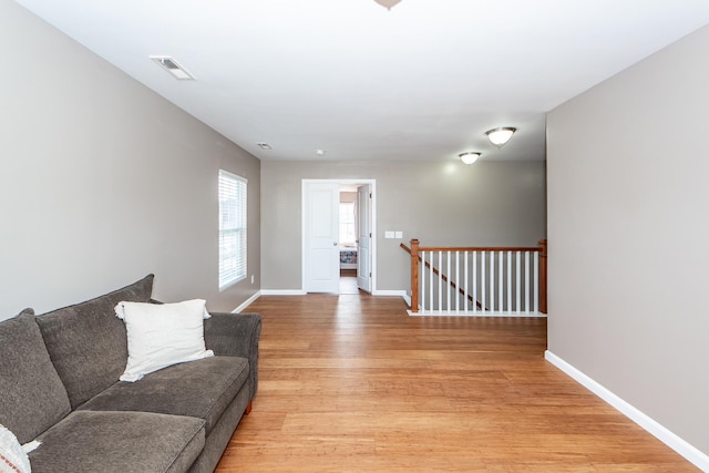 living area featuring light wood-type flooring, visible vents, and baseboards