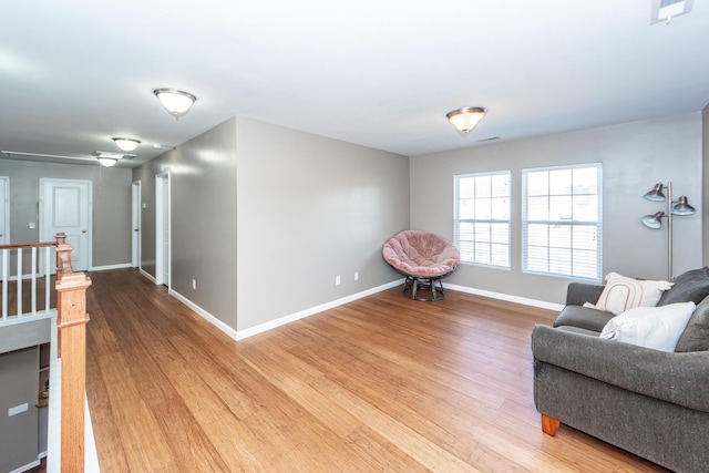 living area with wood finished floors, an upstairs landing, and baseboards