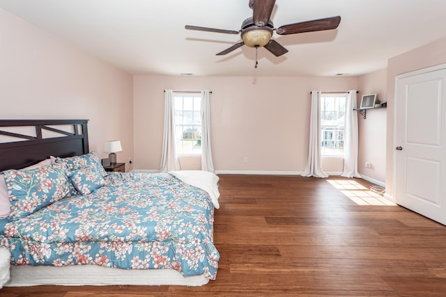 bedroom with dark wood-style flooring, multiple windows, ceiling fan, and baseboards