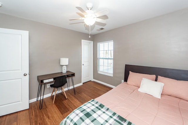 bedroom featuring a ceiling fan, visible vents, baseboards, and wood finished floors