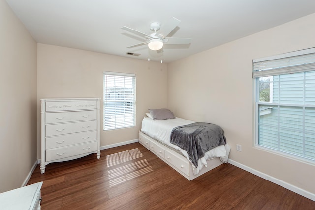 bedroom with a ceiling fan, dark wood-style flooring, visible vents, and baseboards