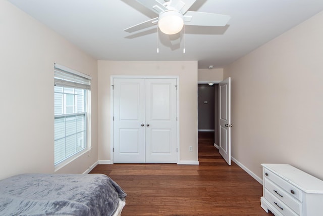 bedroom with a ceiling fan, a closet, baseboards, and dark wood-style flooring