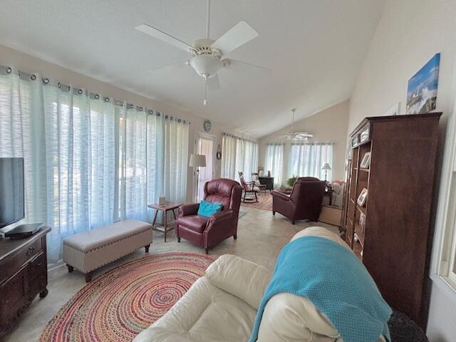 living area featuring ceiling fan, plenty of natural light, and vaulted ceiling