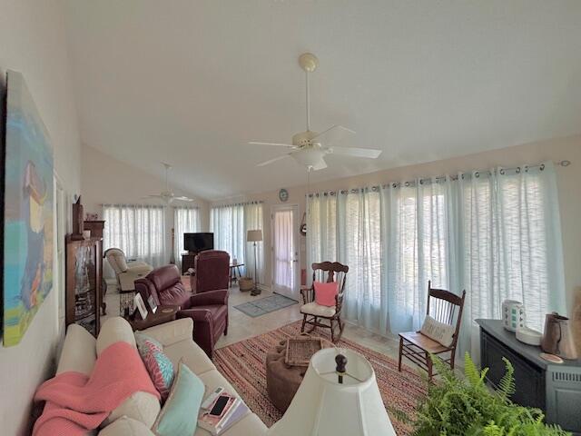 living area with a ceiling fan and vaulted ceiling