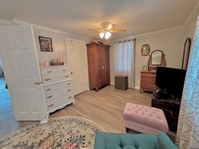 living room with ornamental molding, a ceiling fan, light wood finished floors, and a textured ceiling