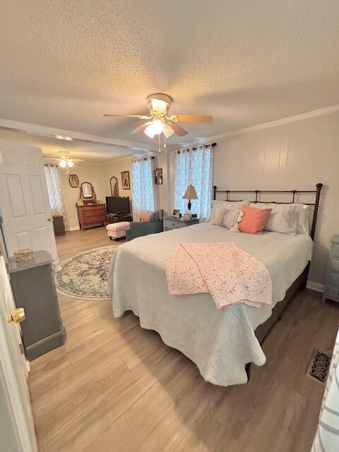 bedroom featuring wood finished floors, a textured ceiling, ornamental molding, and a ceiling fan