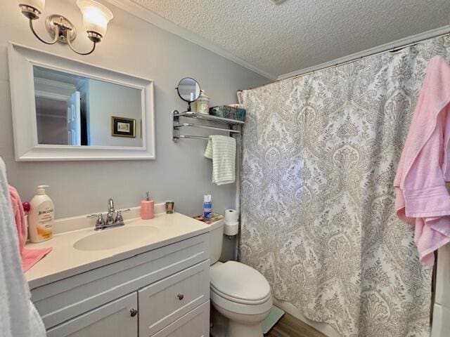 bathroom with a textured ceiling, crown molding, vanity, toilet, and wood finished floors
