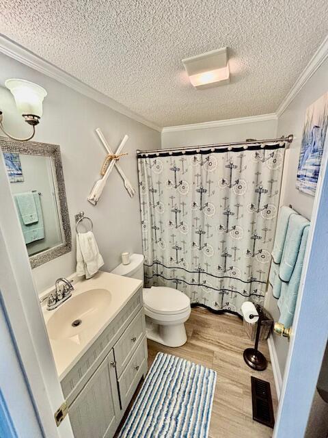 full bathroom featuring vanity, wood finished floors, ornamental molding, a textured ceiling, and toilet