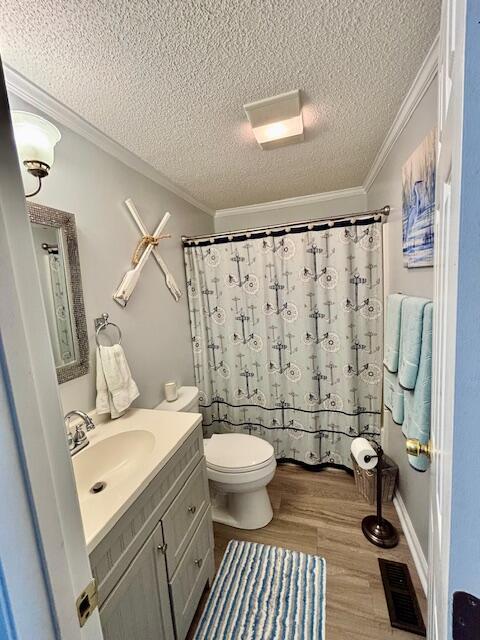 full bath with a textured ceiling, vanity, toilet, wood finished floors, and ornamental molding