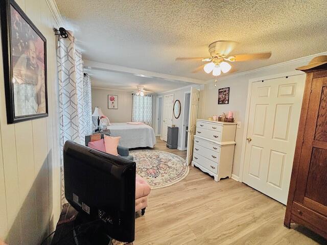 bedroom featuring crown molding, a textured ceiling, light wood finished floors, and ceiling fan