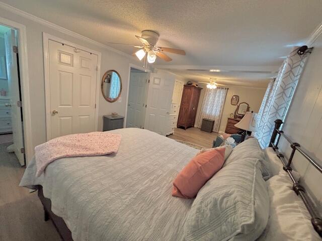bedroom with ornamental molding, a ceiling fan, light wood-type flooring, and a textured ceiling