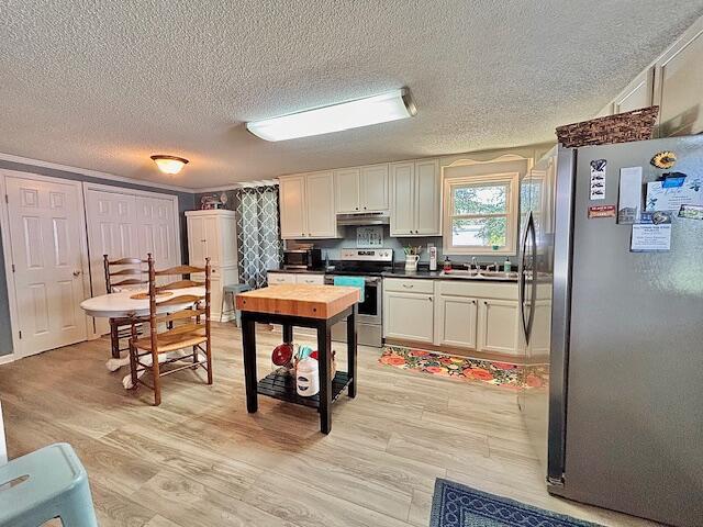 kitchen with appliances with stainless steel finishes, under cabinet range hood, a textured ceiling, light wood-type flooring, and white cabinetry