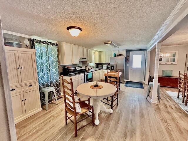 dining space featuring crown molding, light wood-style flooring, and a textured ceiling