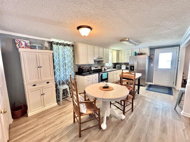 dining space featuring light wood-style flooring, a textured ceiling, and crown molding