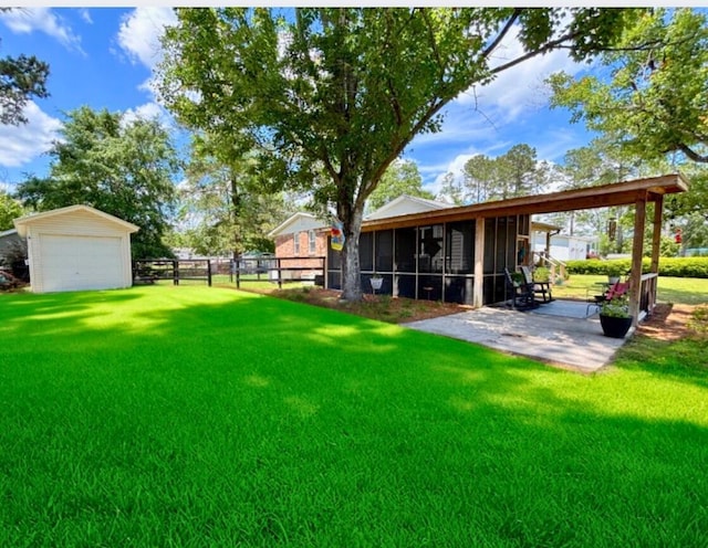 view of yard featuring a sunroom, a detached garage, and a patio area