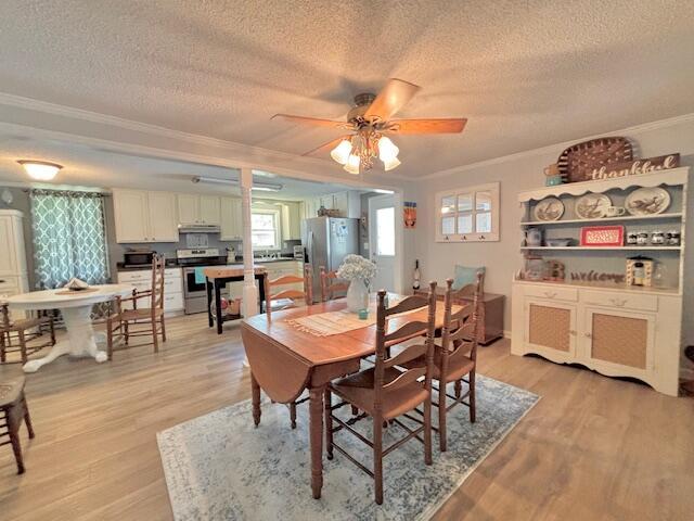 dining room featuring ornamental molding, a textured ceiling, light wood-type flooring, and ceiling fan