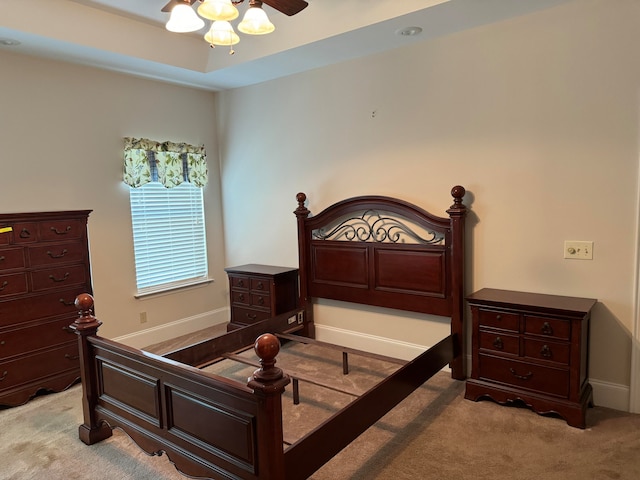 carpeted bedroom with ceiling fan and a raised ceiling