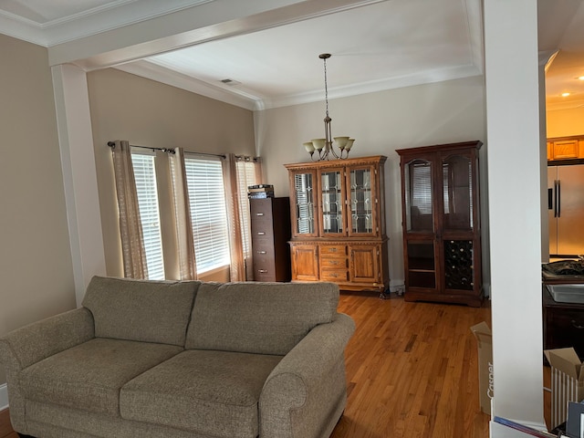 living room with crown molding, light wood-type flooring, and a notable chandelier