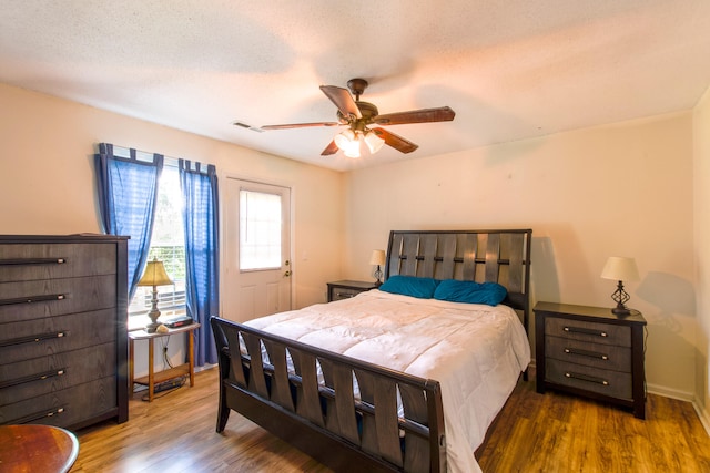 bedroom featuring a textured ceiling, ceiling fan, and dark hardwood / wood-style flooring