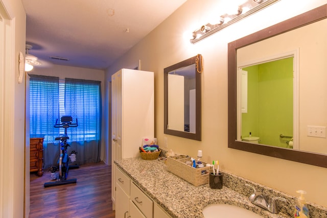 bathroom featuring a textured ceiling, vanity, toilet, hardwood / wood-style flooring, and ceiling fan