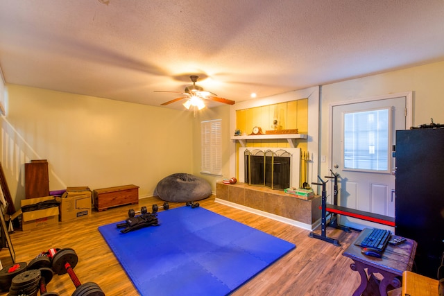 exercise area featuring a textured ceiling, ceiling fan, and wood-type flooring