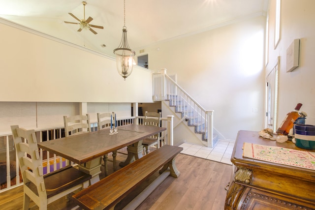 dining space with ceiling fan, ornamental molding, high vaulted ceiling, and hardwood / wood-style flooring