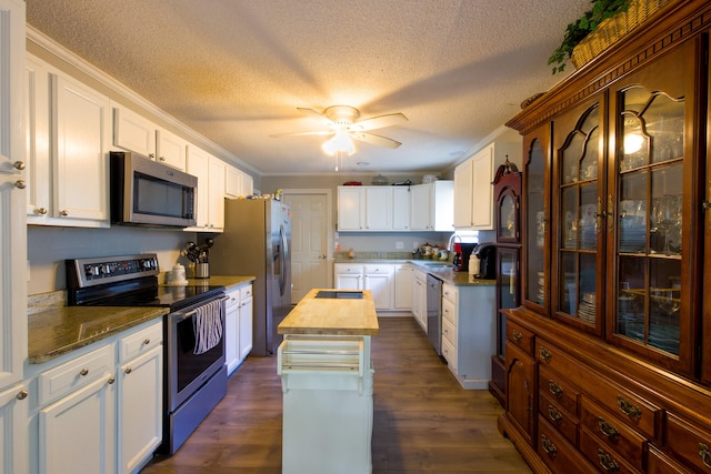 kitchen featuring dark wood-type flooring, appliances with stainless steel finishes, white cabinetry, and ceiling fan