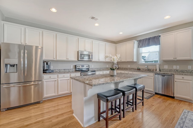 109 Cypress Plantation Rd, Moncks Corner, SC 29461 - kitchen featuring appliances with stainless steel finishes, light wood-style flooring, white cabinetry, a kitchen breakfast bar, and recessed lighting