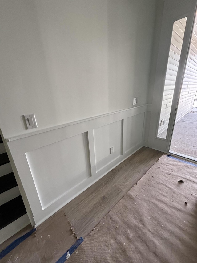 entryway featuring a wainscoted wall, a decorative wall, and wood finished floors