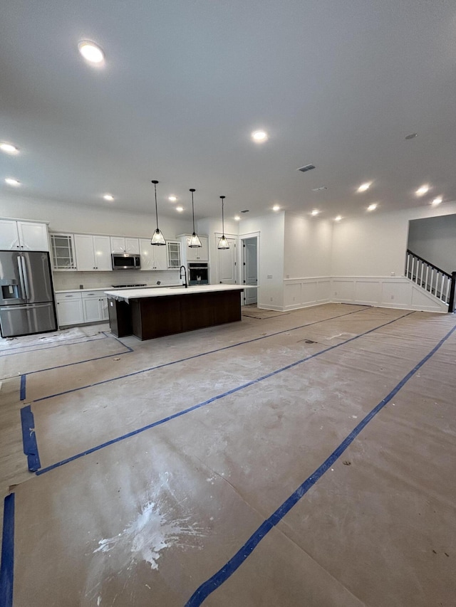 kitchen featuring stainless steel appliances, recessed lighting, light countertops, a kitchen island with sink, and white cabinetry