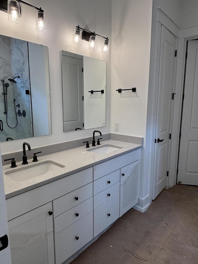 bathroom featuring double vanity, a sink, and a shower with shower door