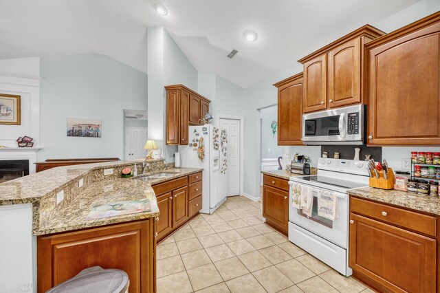 kitchen with vaulted ceiling, light stone counters, light tile patterned floors, and white appliances