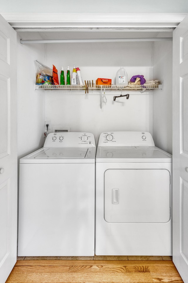 washroom with laundry area, washer and clothes dryer, and light wood-style flooring