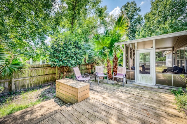 wooden terrace with a sunroom and a fenced backyard