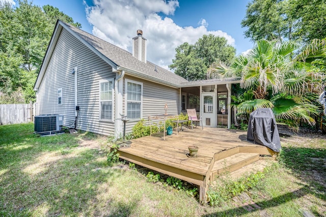 rear view of property with a deck, central air condition unit, fence, a lawn, and a chimney