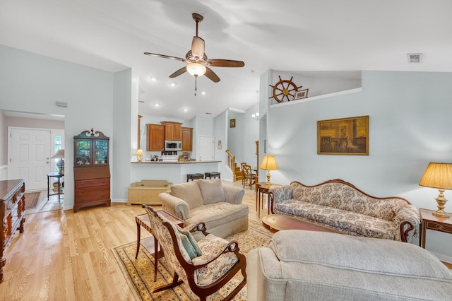 living area with light wood finished floors, visible vents, a ceiling fan, baseboards, and stairs