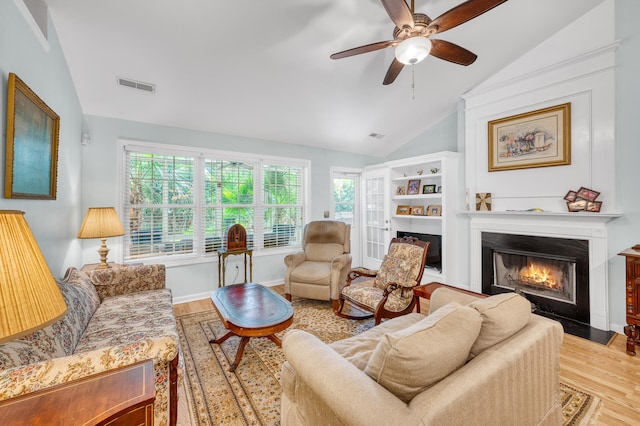 living room featuring light hardwood / wood-style flooring, ceiling fan, a wealth of natural light, and vaulted ceiling