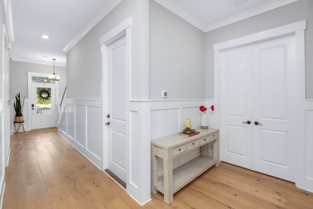 hallway with a notable chandelier, crown molding, and light hardwood / wood-style flooring