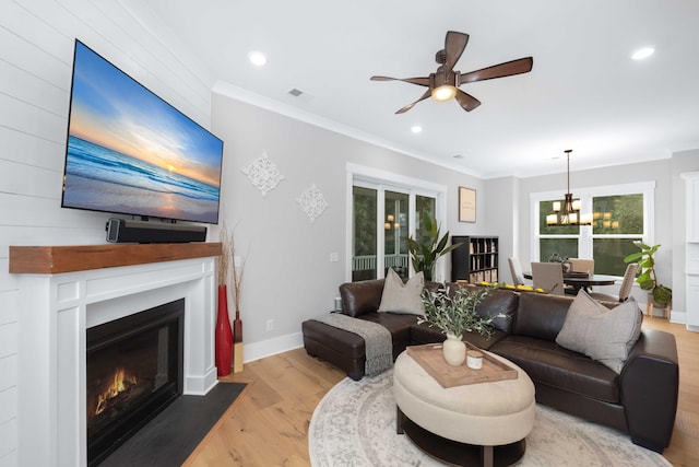 living room with a wealth of natural light, ornamental molding, and light hardwood / wood-style flooring