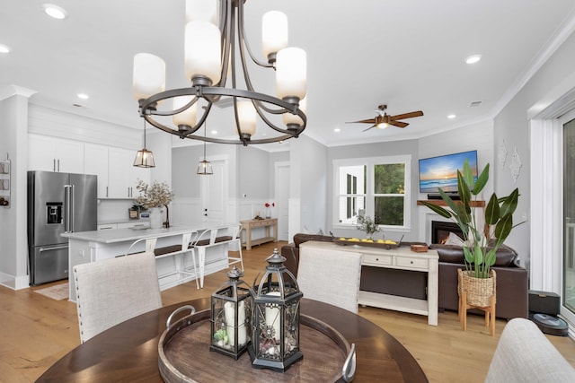 dining space with ceiling fan with notable chandelier, light hardwood / wood-style floors, and crown molding