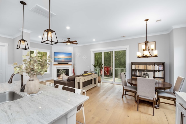 kitchen with crown molding, light hardwood / wood-style floors, sink, and decorative light fixtures