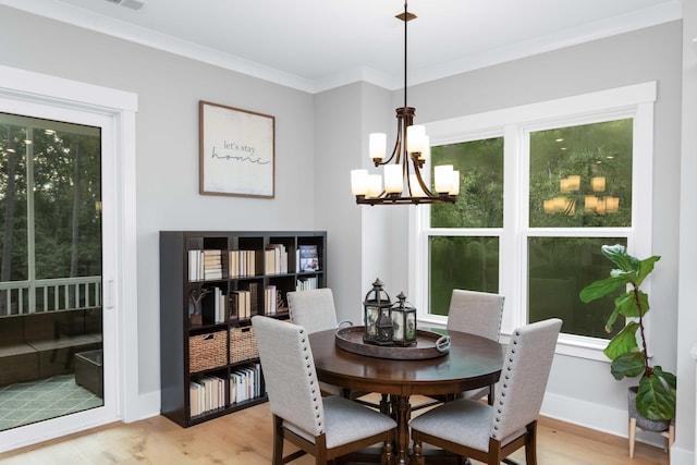 dining area featuring light wood-type flooring, a notable chandelier, and crown molding