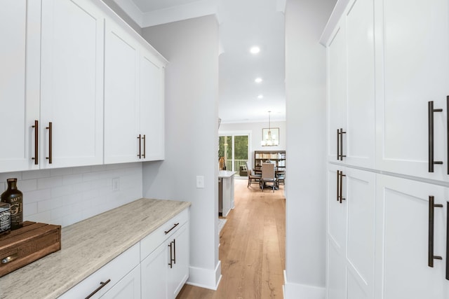 bar with white cabinetry, backsplash, pendant lighting, light stone countertops, and light hardwood / wood-style flooring