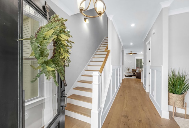 interior space featuring ornamental molding, ceiling fan with notable chandelier, and hardwood / wood-style flooring