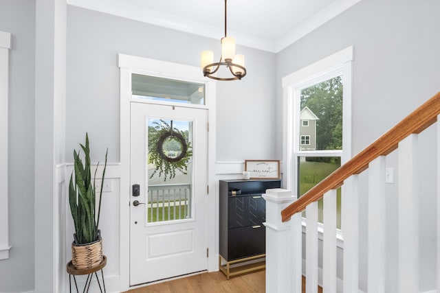 foyer with a chandelier, light hardwood / wood-style floors, and crown molding