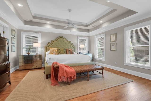 bedroom with crown molding, ceiling fan, light hardwood / wood-style floors, and a raised ceiling