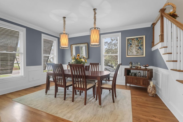 dining area featuring hardwood / wood-style flooring, ornamental molding, and a healthy amount of sunlight